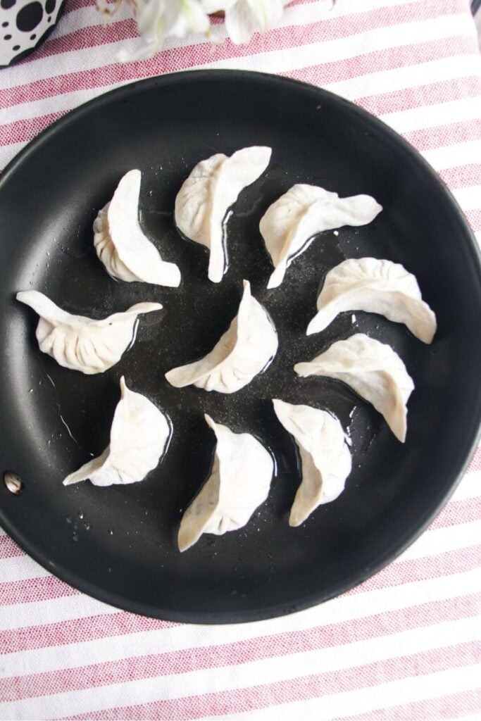 Cheeseburger dumplings arranged in a circle in a small pan.