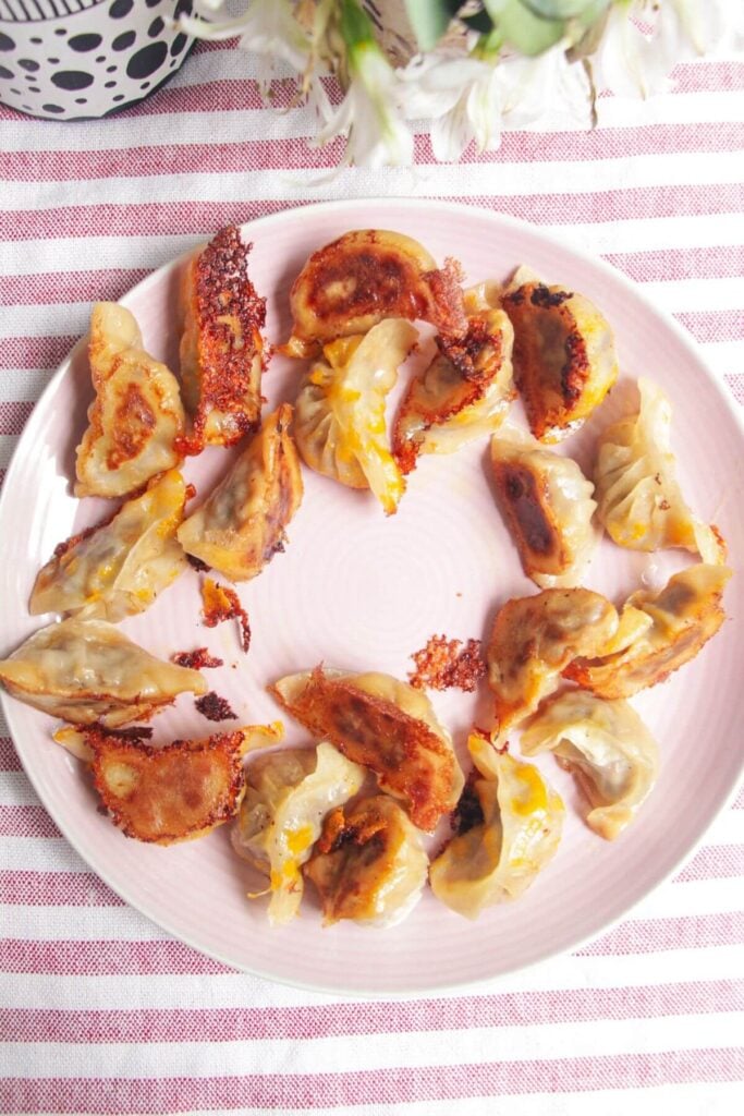 Crispy cheeseburger dumplings in a circle on a pink plate.
