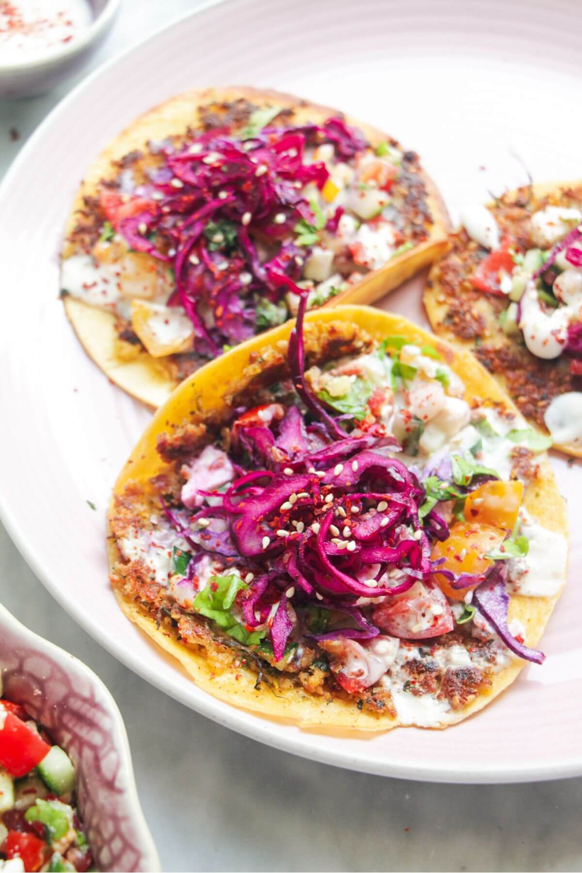 Four smash falafel tacos on a pink plate.