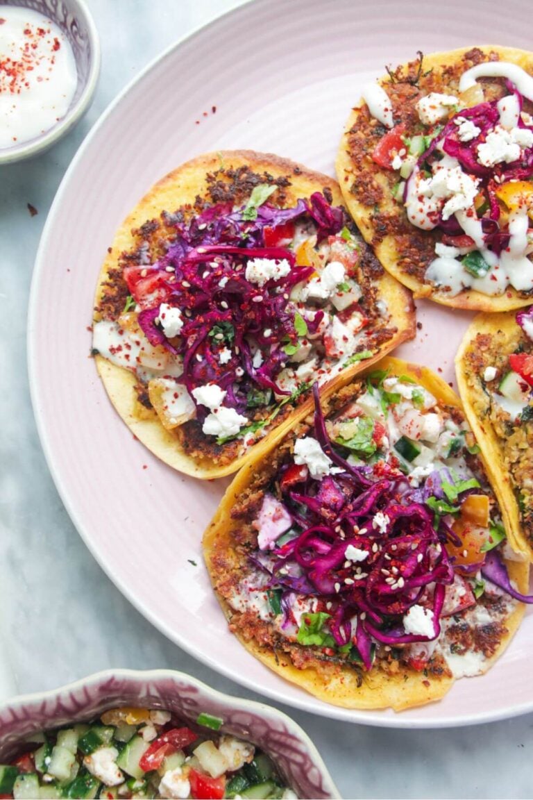 Four smash falafel tacos on a pink plate.