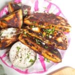 Three stuffed flatbreads on a pink and white plate with tahini sauce on the side.