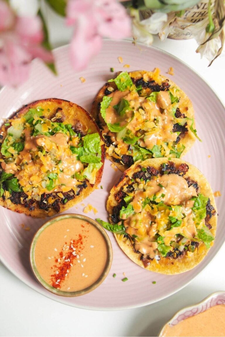 Three smash cheeseburger tacos on a pink plate.