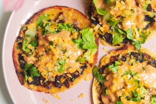 Three smash cheeseburger tacos on a pink plate.