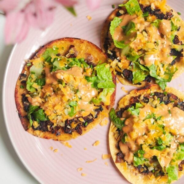 Three smash cheeseburger tacos on a pink plate.