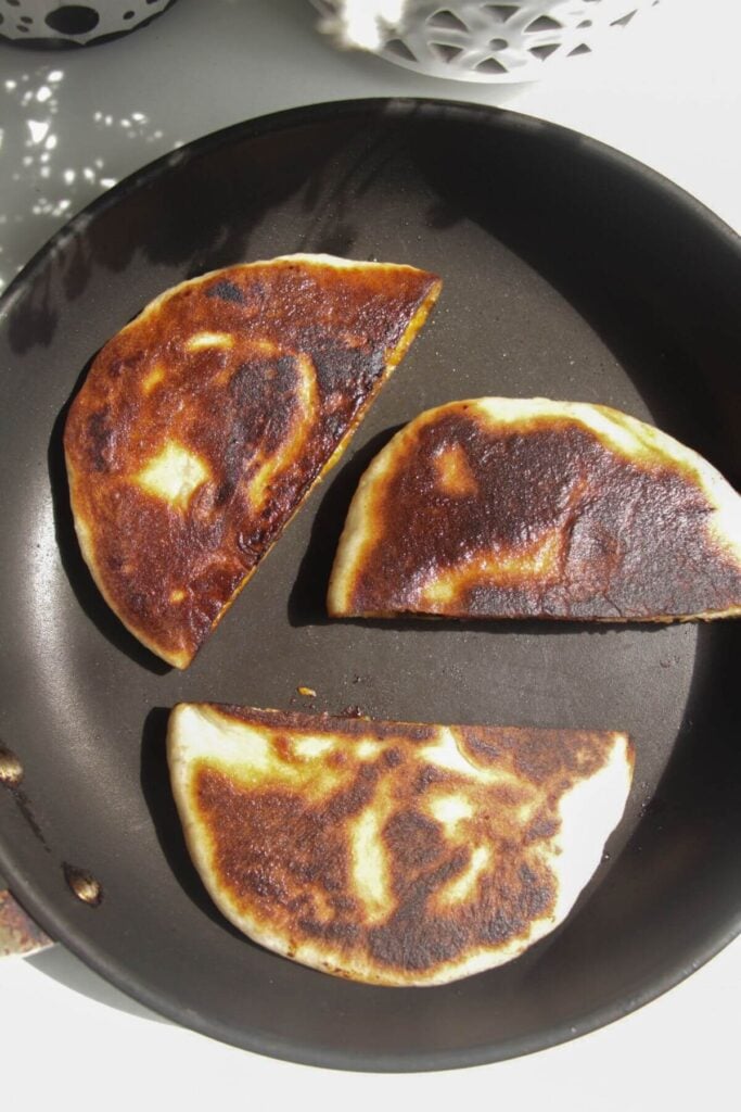 Three stuffed flatbreads in a small pan.