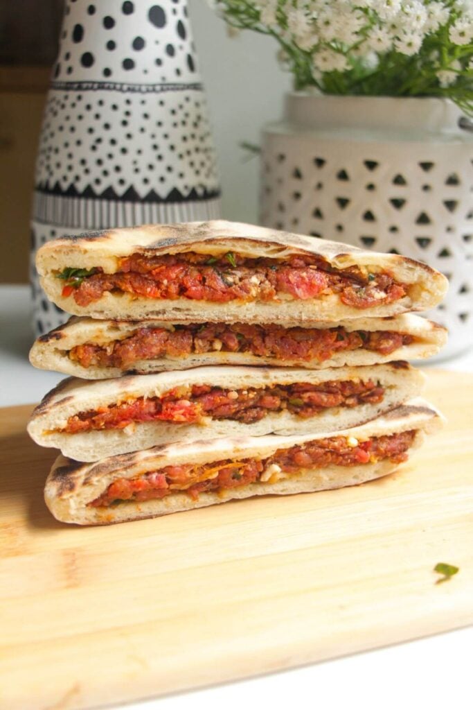 Three stuffed flatbreads on top of each other on a wooden board.