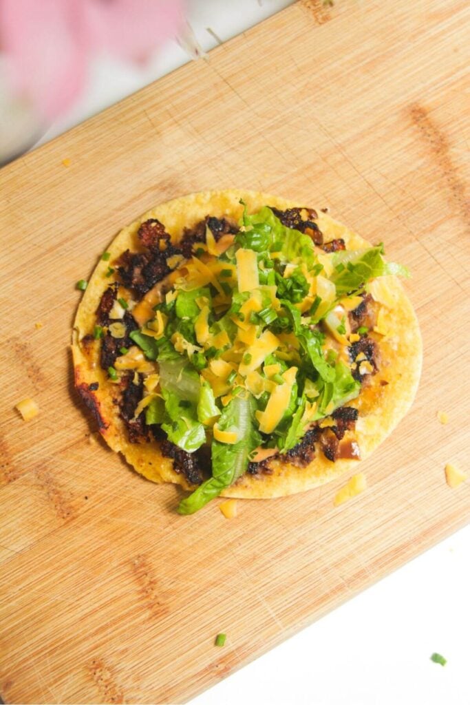 Cheeseburger taco topped with lettuce and cheese.
