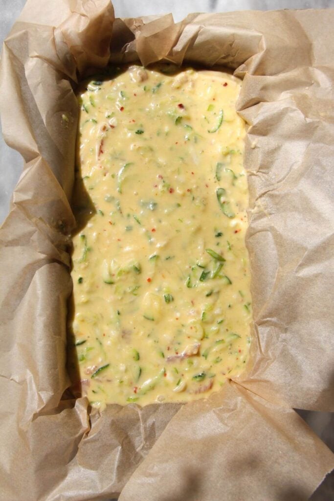 Zucchini bread batter in a lined loaf tin.
