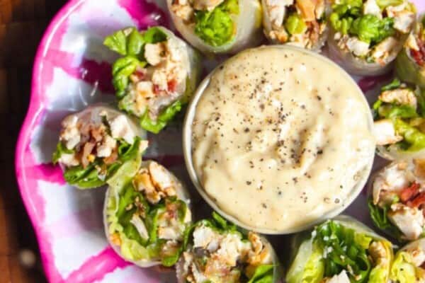 Chicken Caesar rice paper rolls on a pink and white plate.