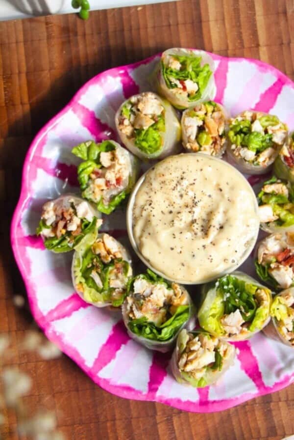 Chicken Caesar rice paper rolls on a pink and white plate.