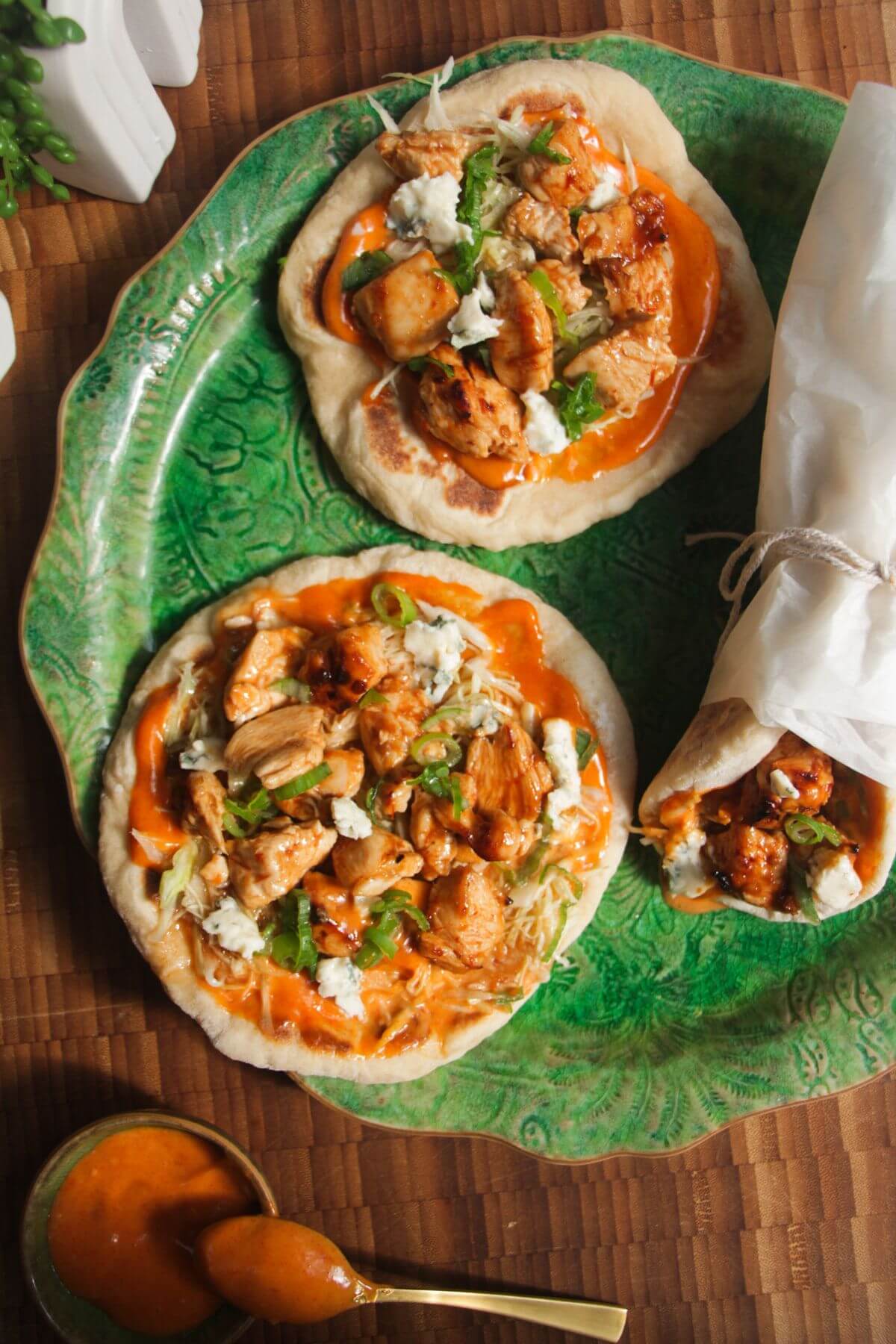 Three Buffalo chicken wraps on a large green platter.