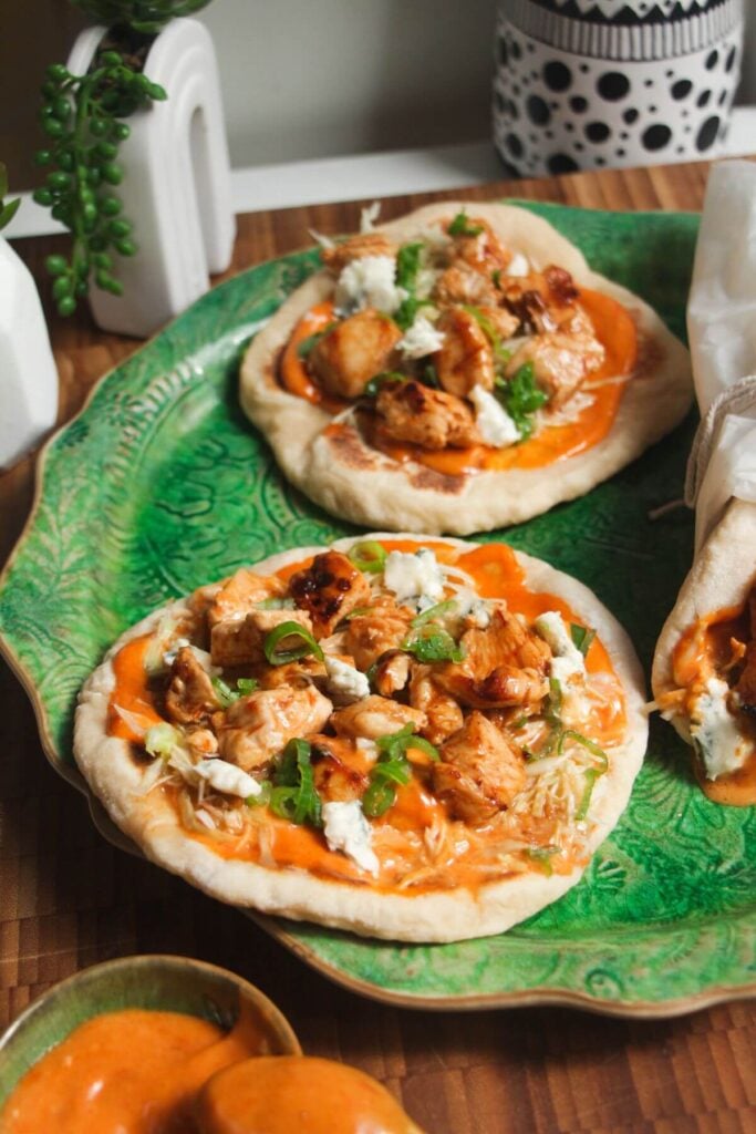 Three Buffalo chicken wraps on a large green platter.