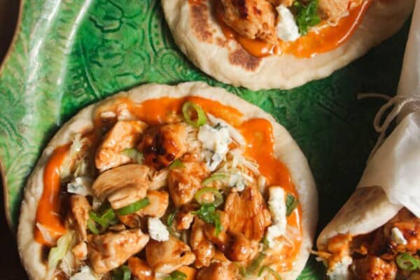Three Buffalo chicken wraps on a large green platter.