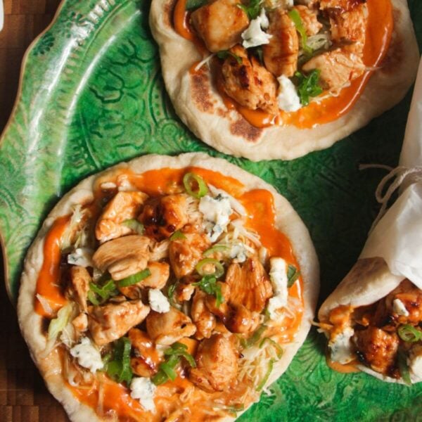 Three Buffalo chicken wraps on a large green platter.
