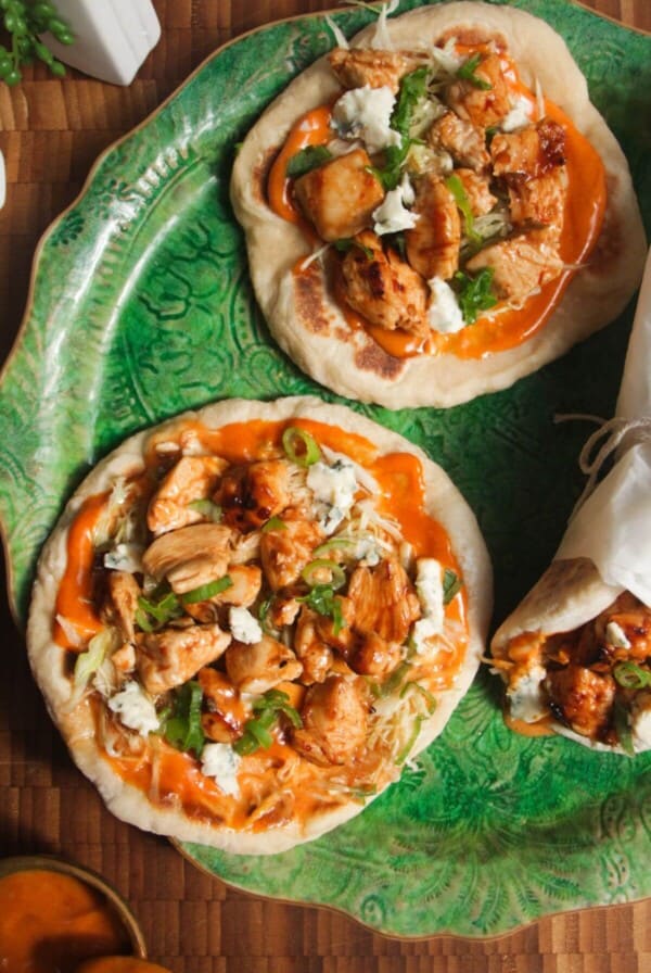 Three Buffalo chicken wraps on a large green platter.