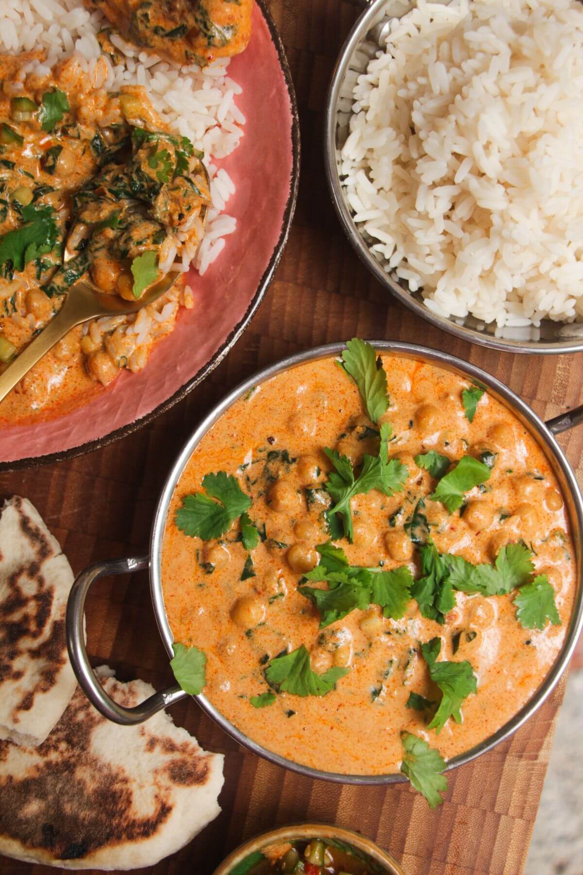 Coconut chickpea curry, rice and naan on a wooden surface.