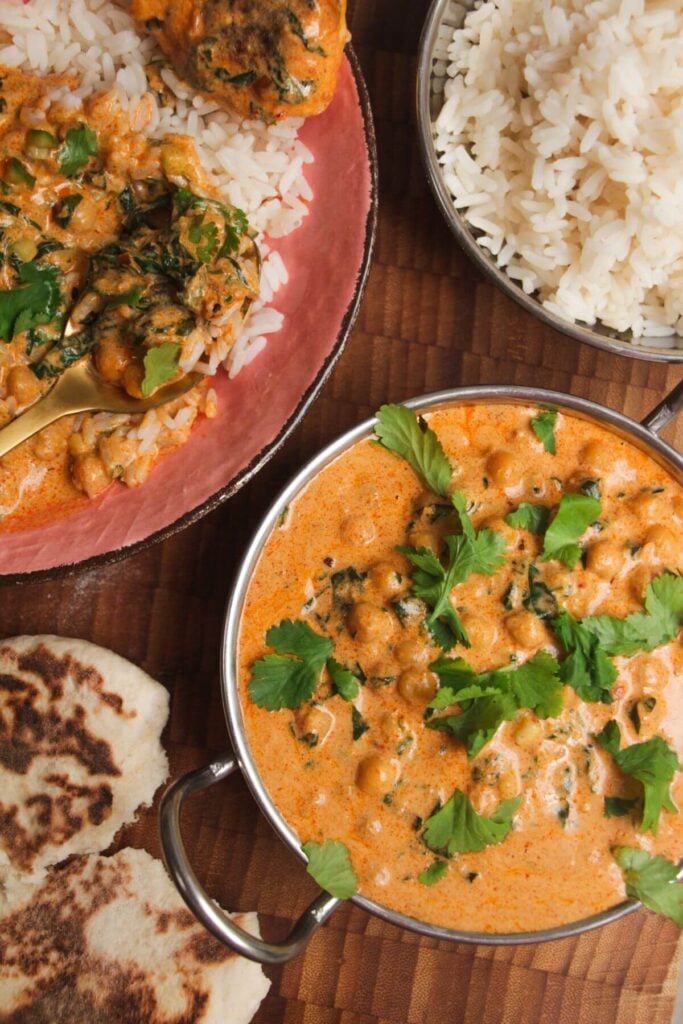 Coconut chickpea curry, rice and naan on a wooden surface.