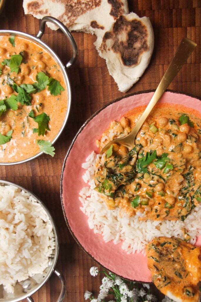 Coconut chickpea curry, rice and naan on a wooden surface.