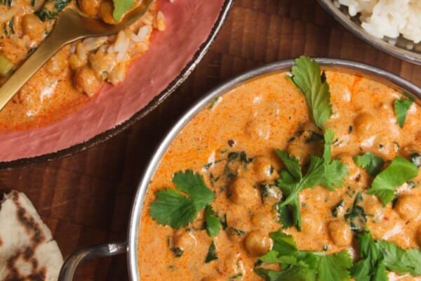 Coconut chickpea curry, rice and naan on a wooden surface.