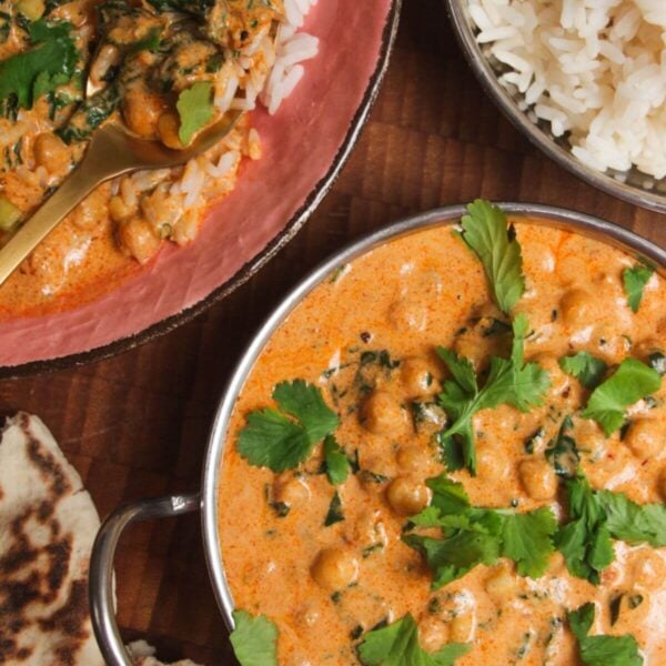Coconut chickpea curry, rice and naan on a wooden surface.
