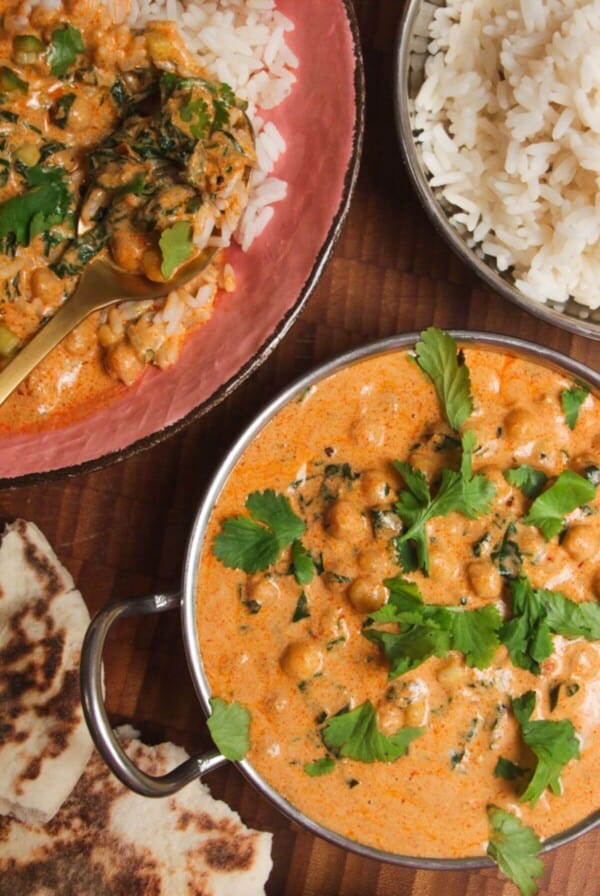 Coconut chickpea curry, rice and naan on a wooden surface.