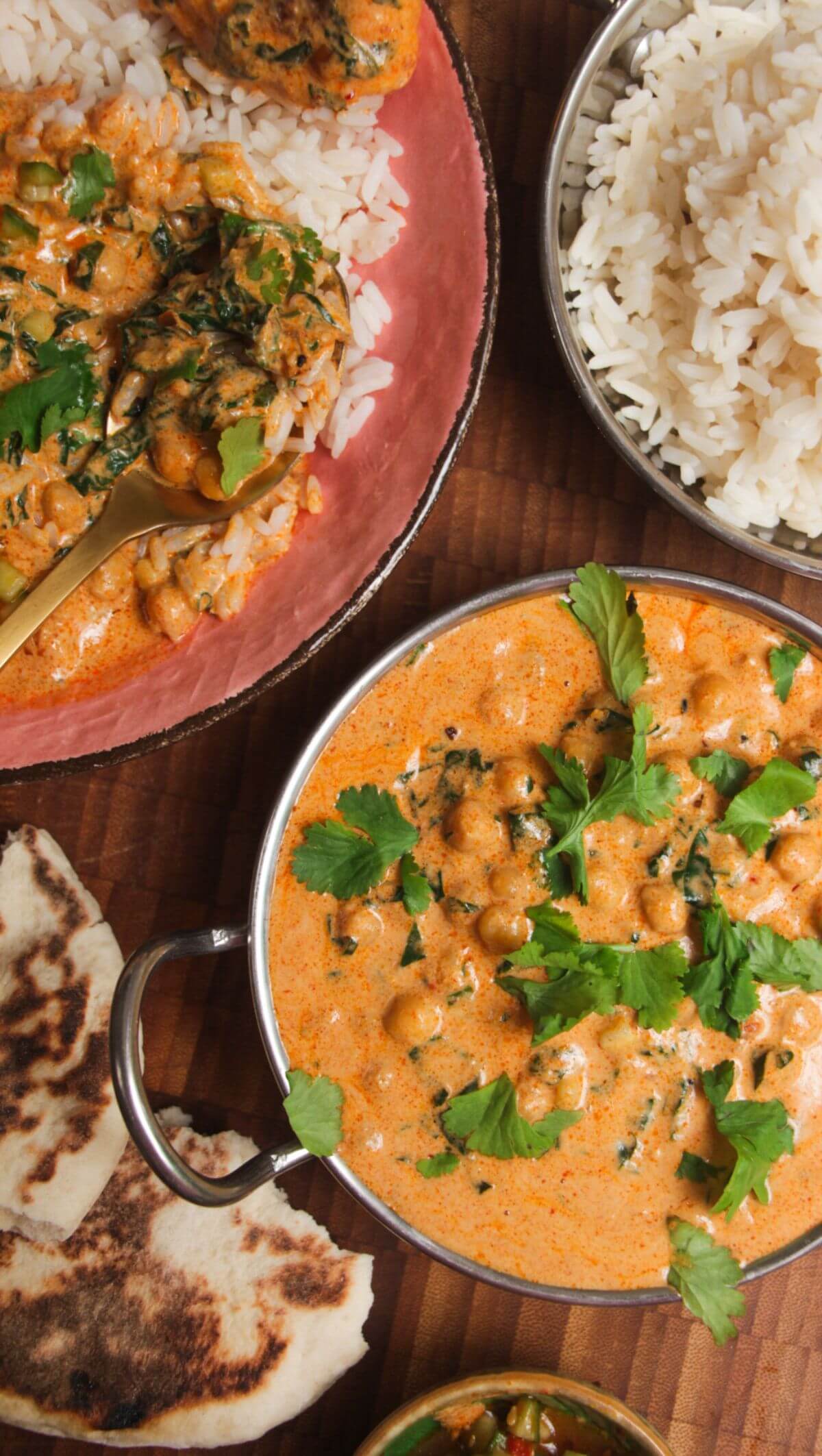Coconut chickpea curry, rice and naan on a wooden surface.