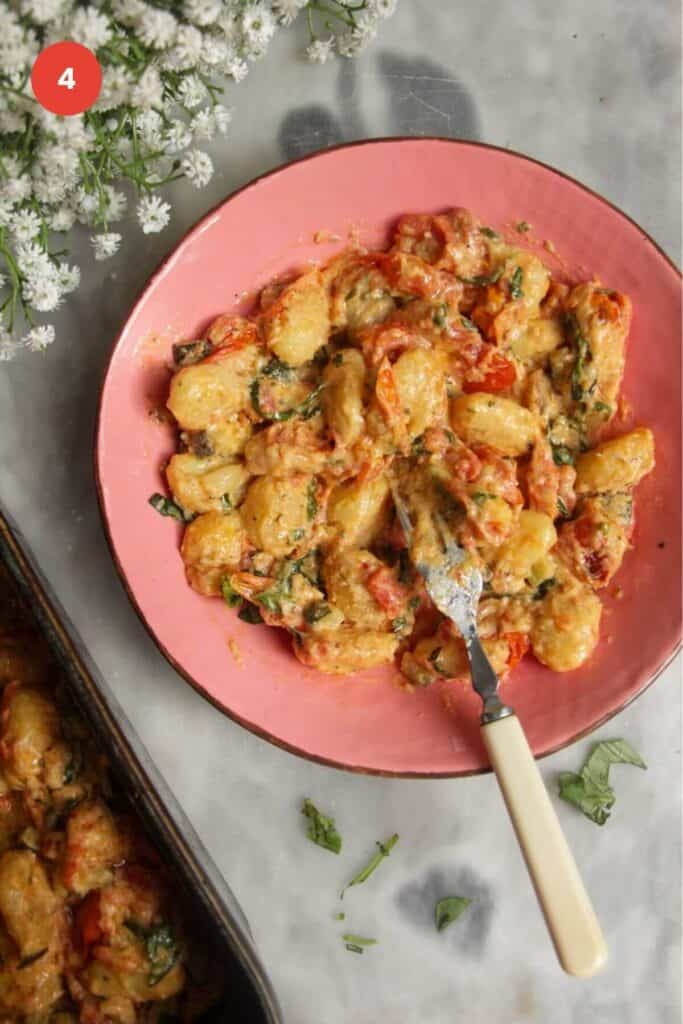 Creamy gnocchi served up in bowl with baking dish on the side.