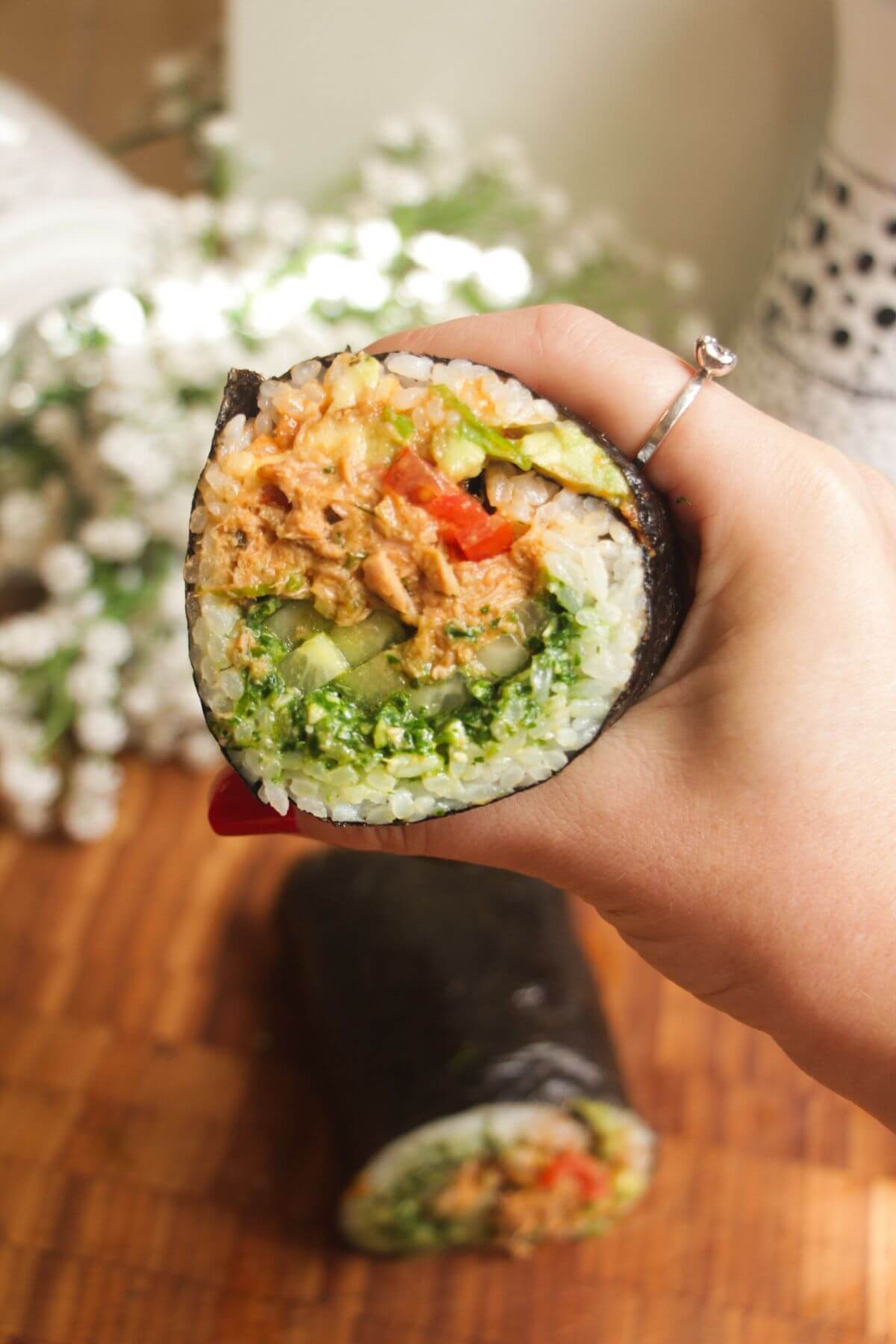 Hand holding sliced sushi burrito.