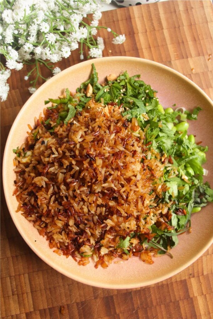 Crispy rice on top of salad in pink bowl.
