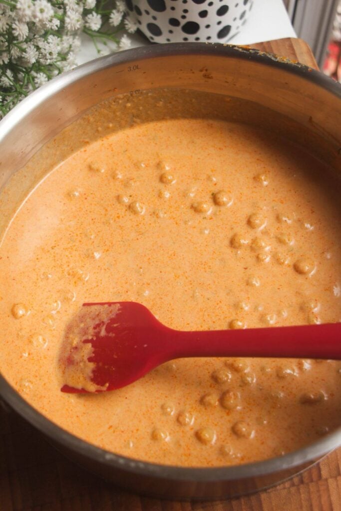 Stirring coconut chickpea curry in large pot.