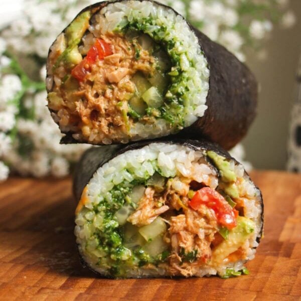Sliced tuna sushi burrito on top of eachother on a wooden board.