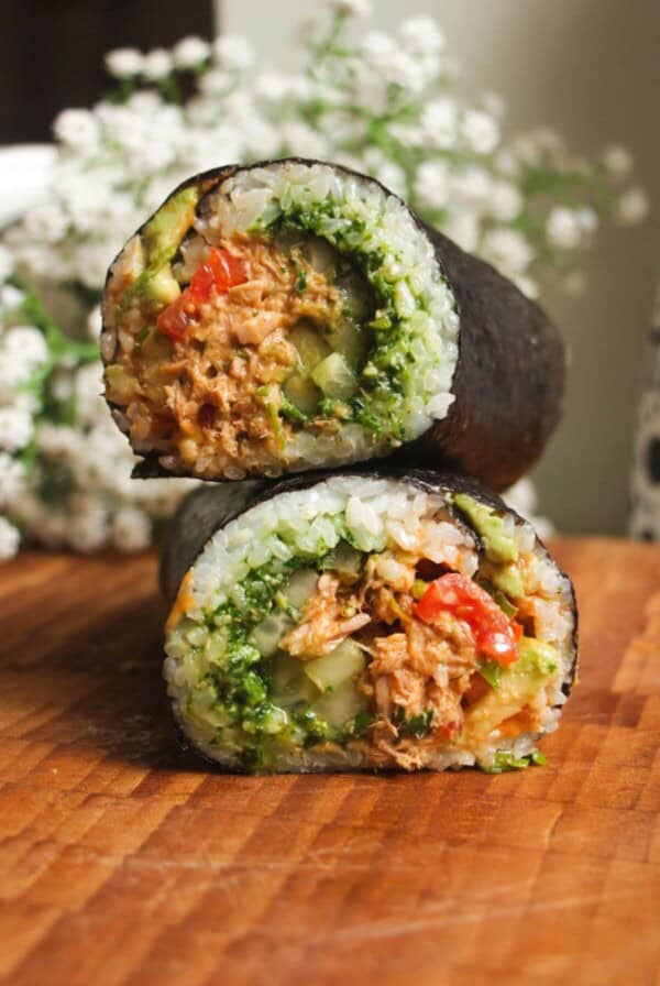 Sliced tuna sushi burrito on top of eachother on a wooden board.