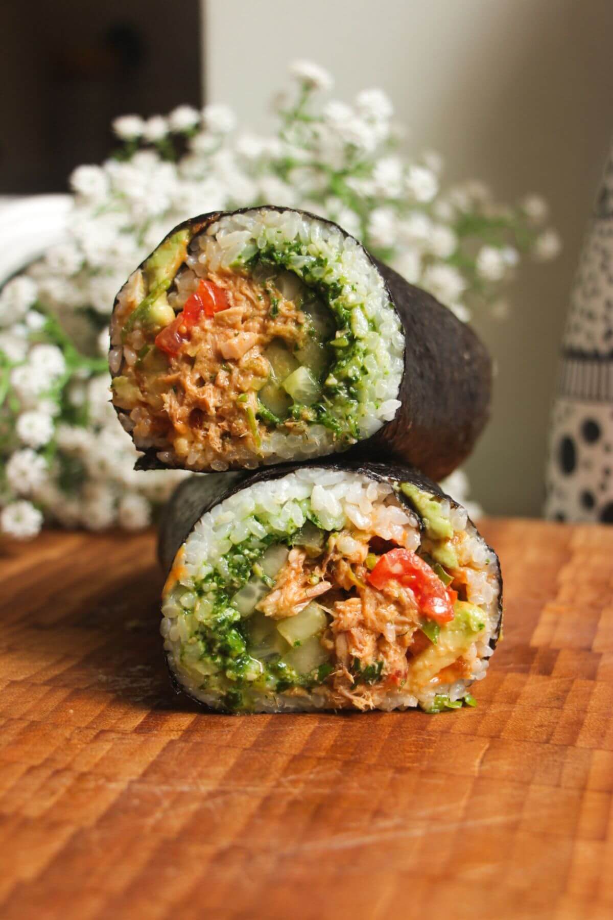 Sliced tuna sushi burrito on top of eachother on a wooden board.