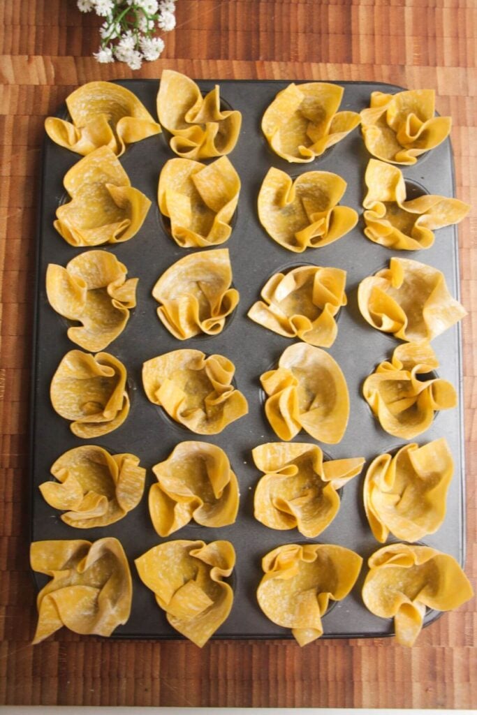 Wonton wrappers pressed into mini muffin tin.