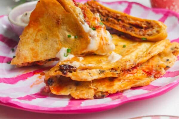 Breakfast tortilla wrap sliced on a pink and white plate.