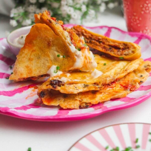 Breakfast tortilla wrap sliced on a pink and white plate.