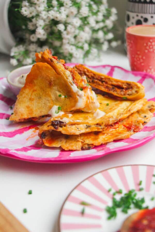 Breakfast tortilla wrap sliced on a pink and white plate.