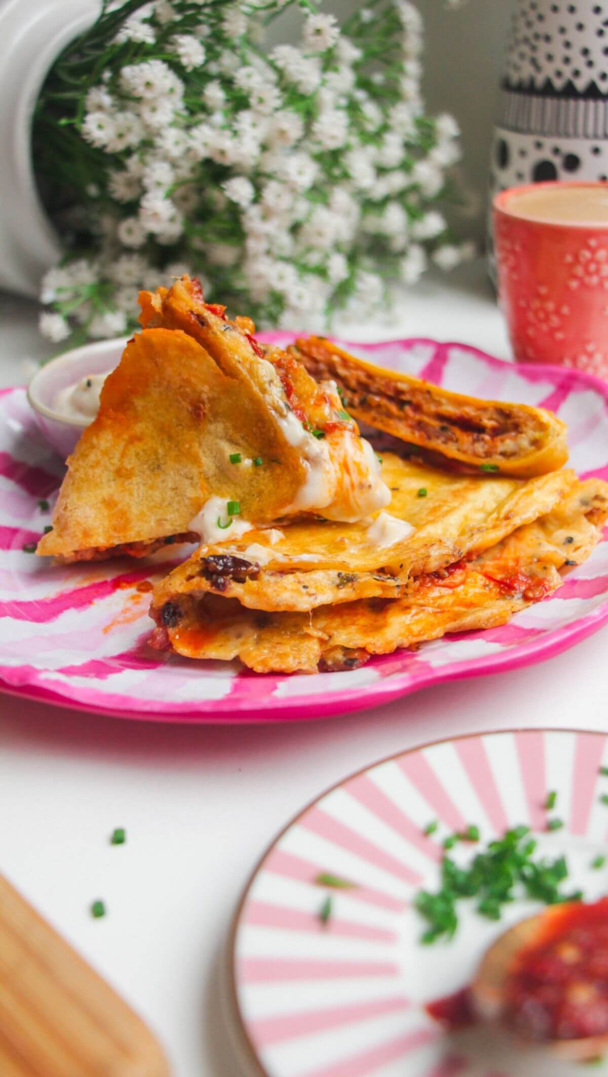 Breakfast tortilla wrap sliced on a pink and white plate.