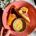 Three cheeseburger spring rolls in a pink plate.