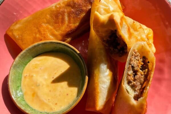 Three cheeseburger spring rolls in a pink plate.