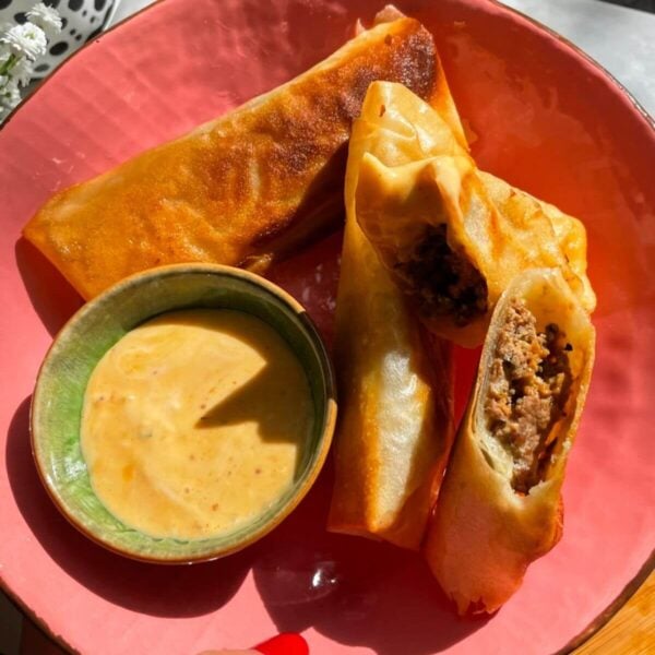 Three cheeseburger spring rolls in a pink plate.