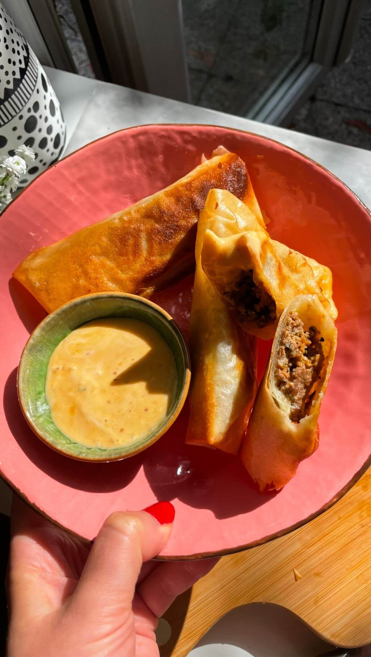Three cheeseburger spring rolls in a pink plate.
