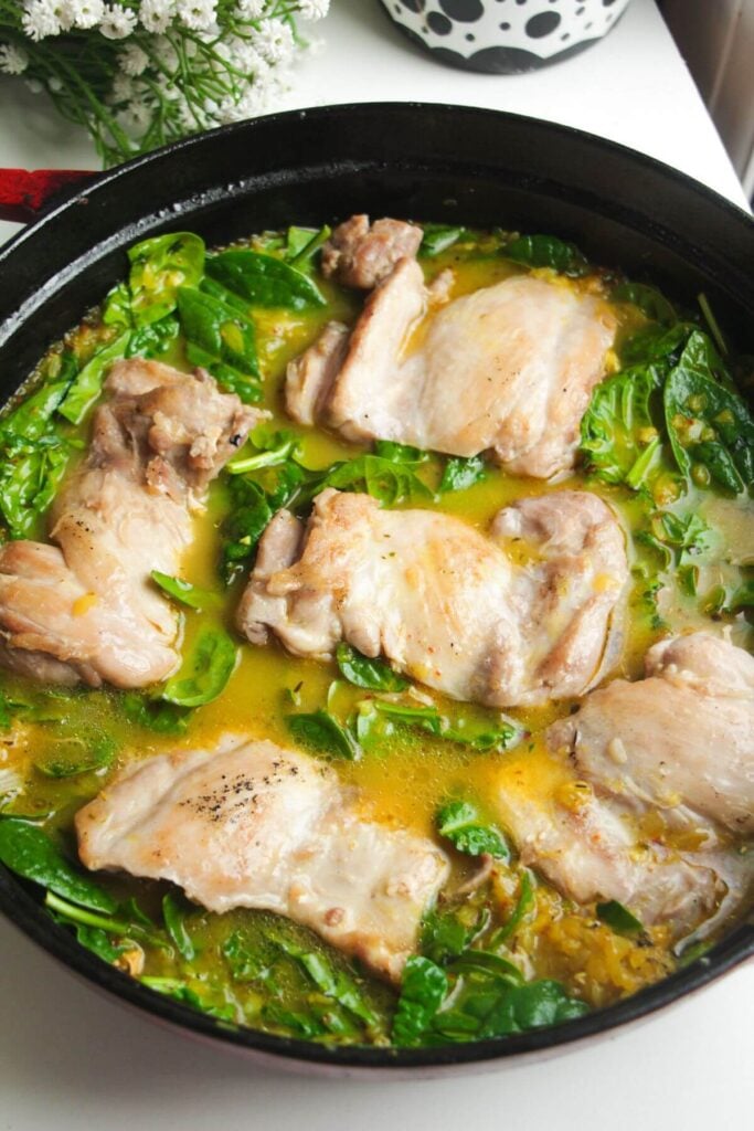 Cooked chicken thighs nestled in stock and rice.