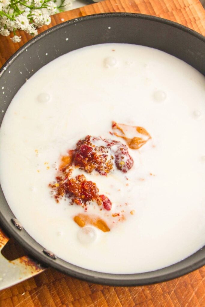 Peanut butter, gochujang paste and coconut milk in a pan.