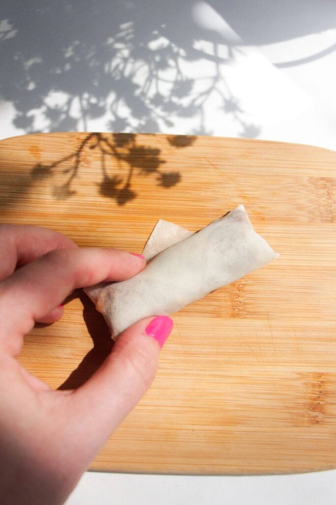 Hand rolling up cheeseburger spring roll.