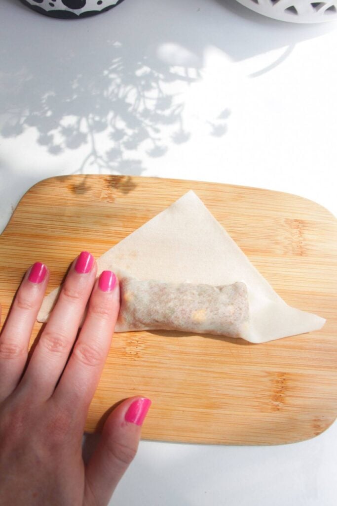 Hands folding up cheeseburger spring roll.