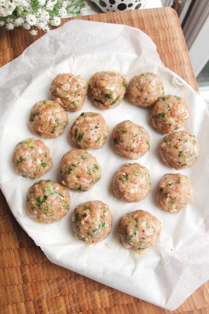 Formed meatballs on a lined plate.