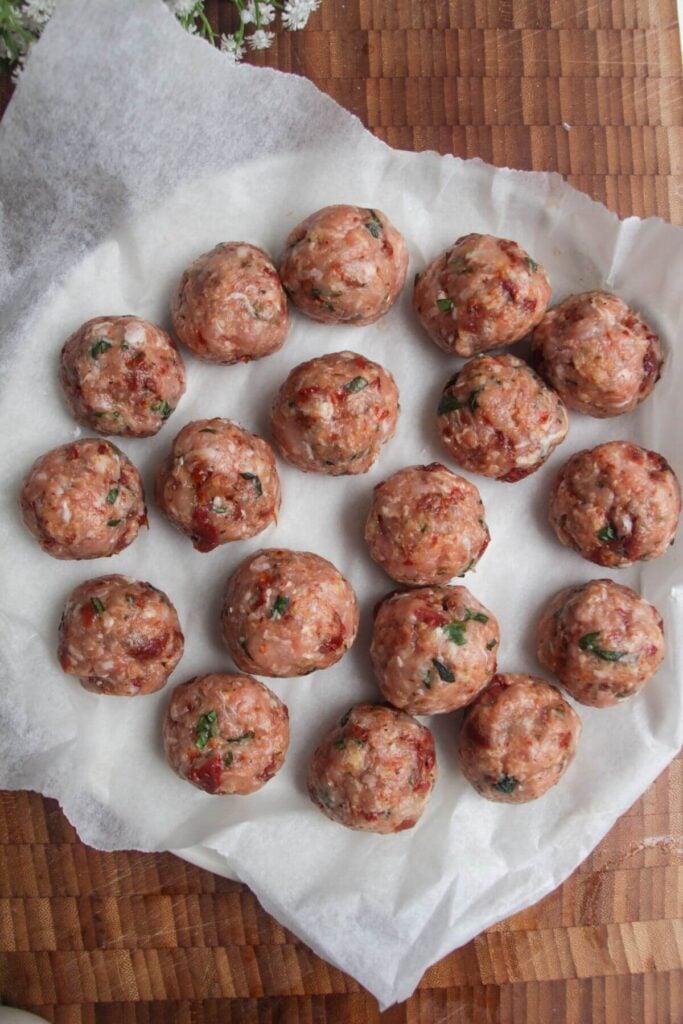 'Marry Me' chicken meatballs formed and sitting on a plate.