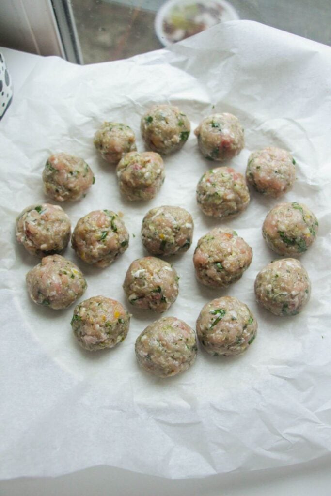 Rolled chicken and pesto meatballs on a lined plate.