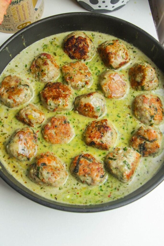 Browned meatballs added back into creamy pesto sauce.
